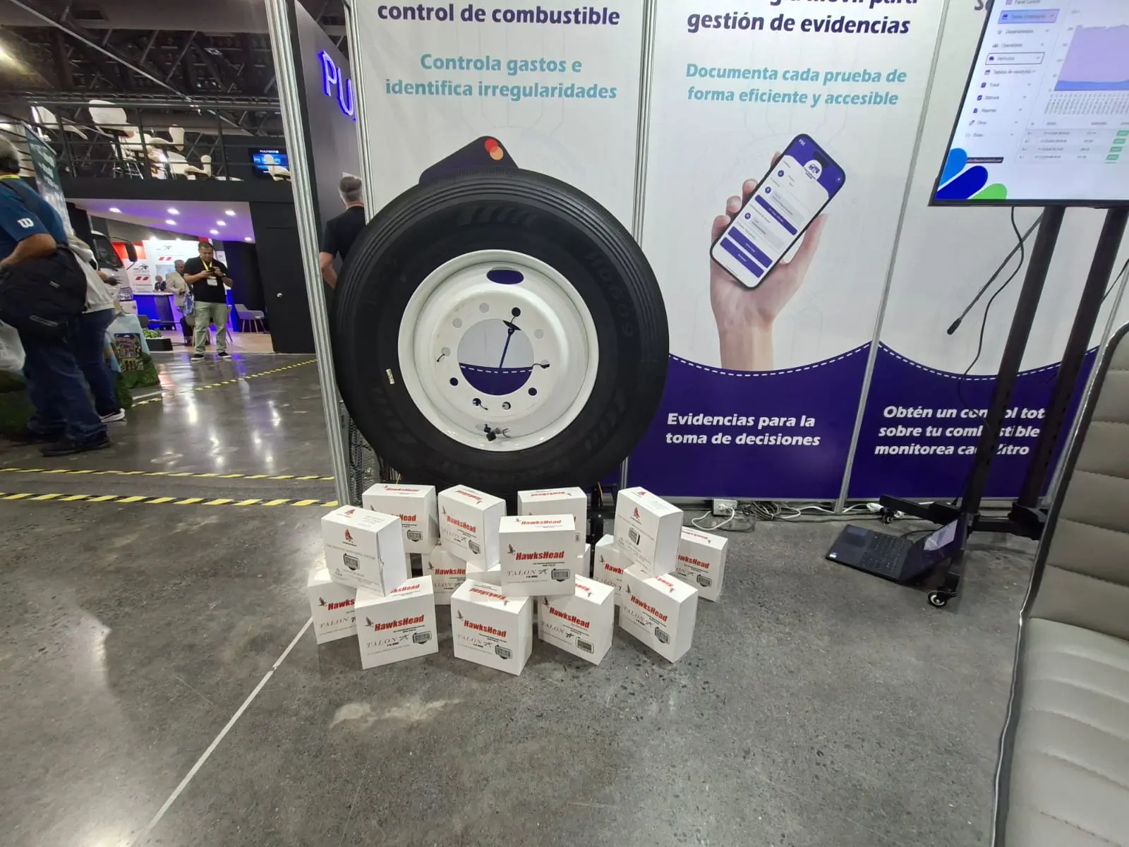 Llanta de camión y sensores TPMS junto a los paneles del stand